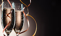 Elegant image closeup of two champagne glasses and ribbons for decoration on a dark background with backlight and copy space