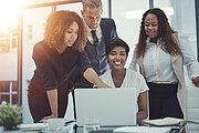 Shot of a group of colleagues using a laptop together in a modern office