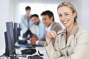 Business woman at work giving you an attractive smile with colleagues in background