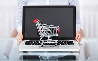 Close-up Of Businessperson With Shopping Cart Over A Laptop